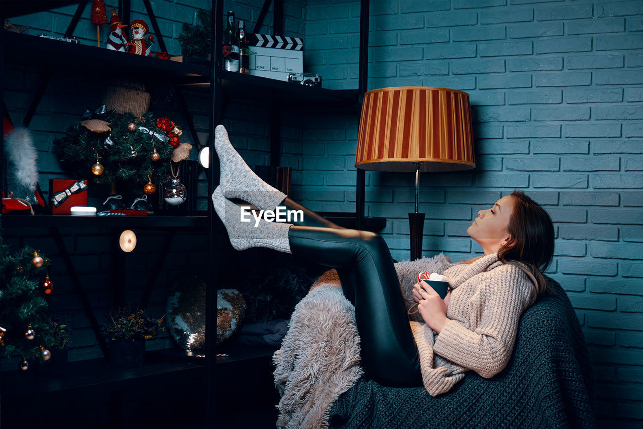 Side view of woman relaxing in sofa at home