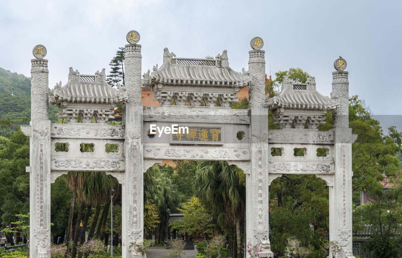 Gate in the ngong ping village with tian tan big buddha in the dstance on lantau island, hong kong