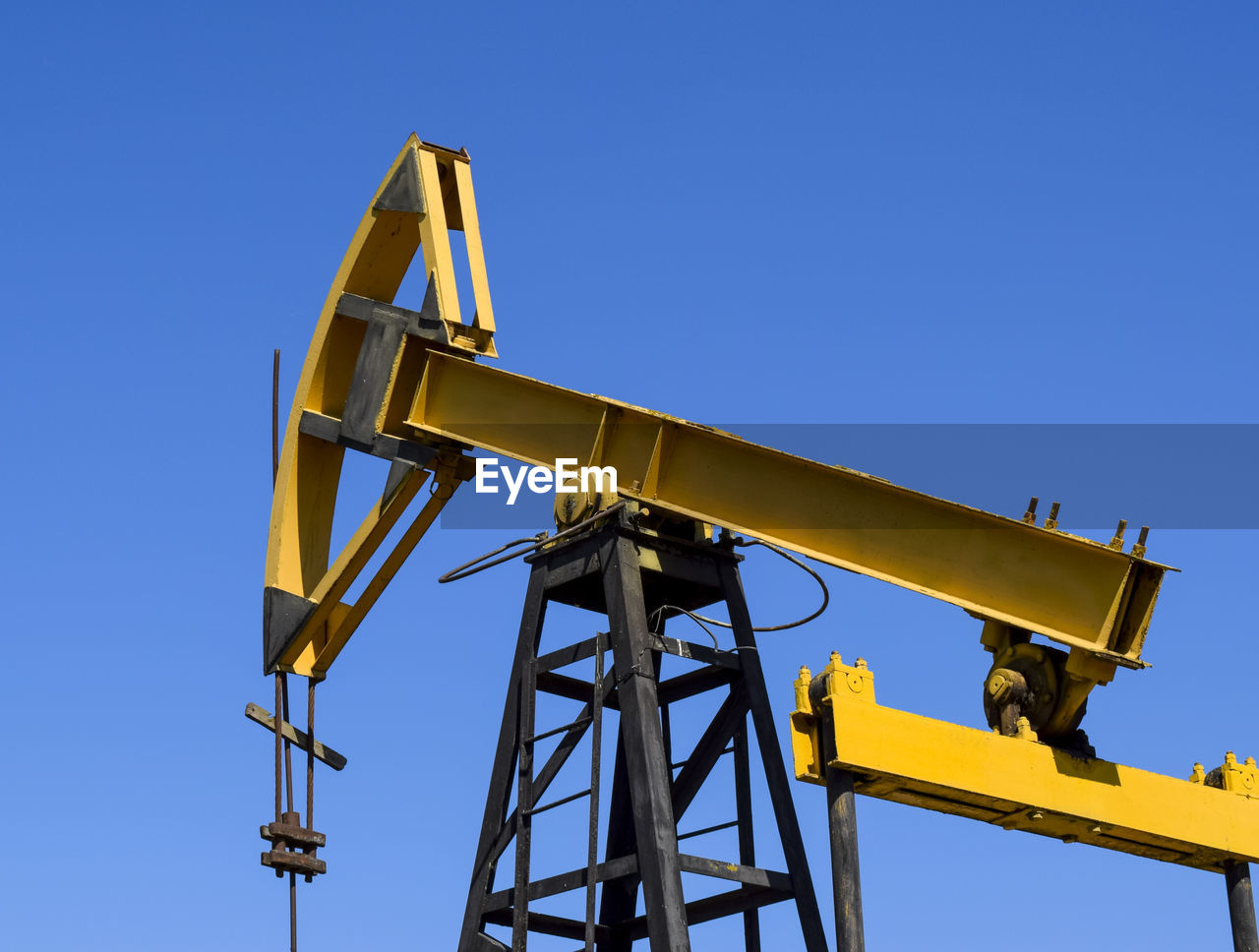 Low angle view of crane against clear blue sky