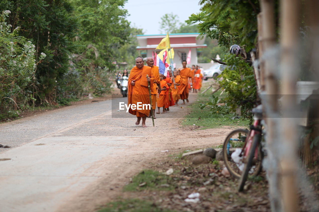 REAR VIEW OF MEN WALKING ON FOOTPATH