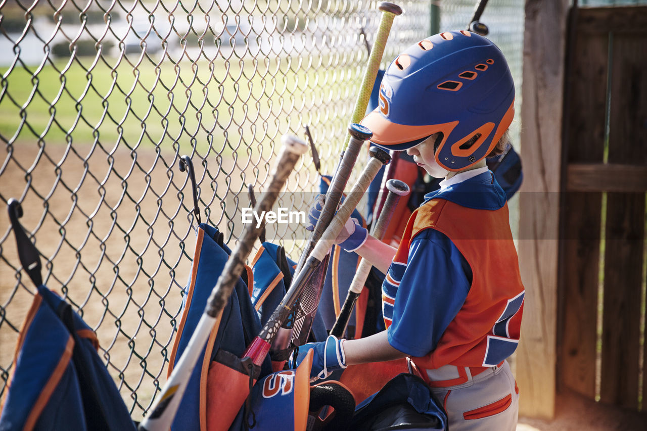 Side view of boy removing baseball bat from bag at field