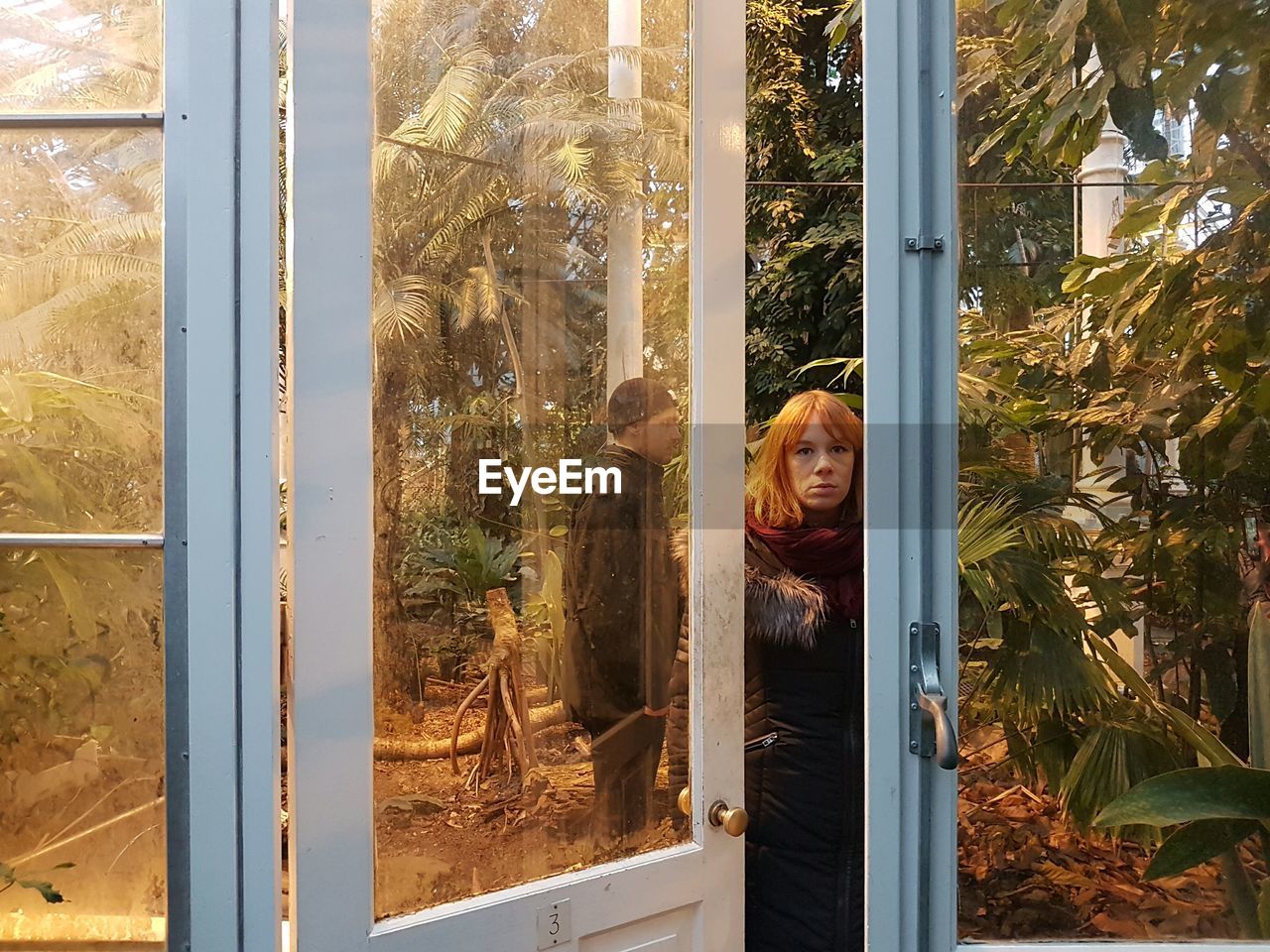 Man and woman in greenhouse seen through door