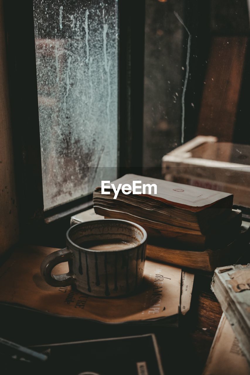 Close-up of coffee cup by window on table