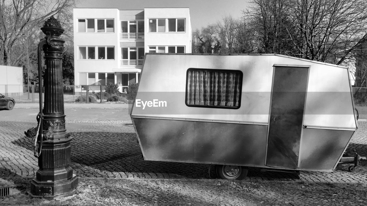 Trailer home by water pump on footpath against building