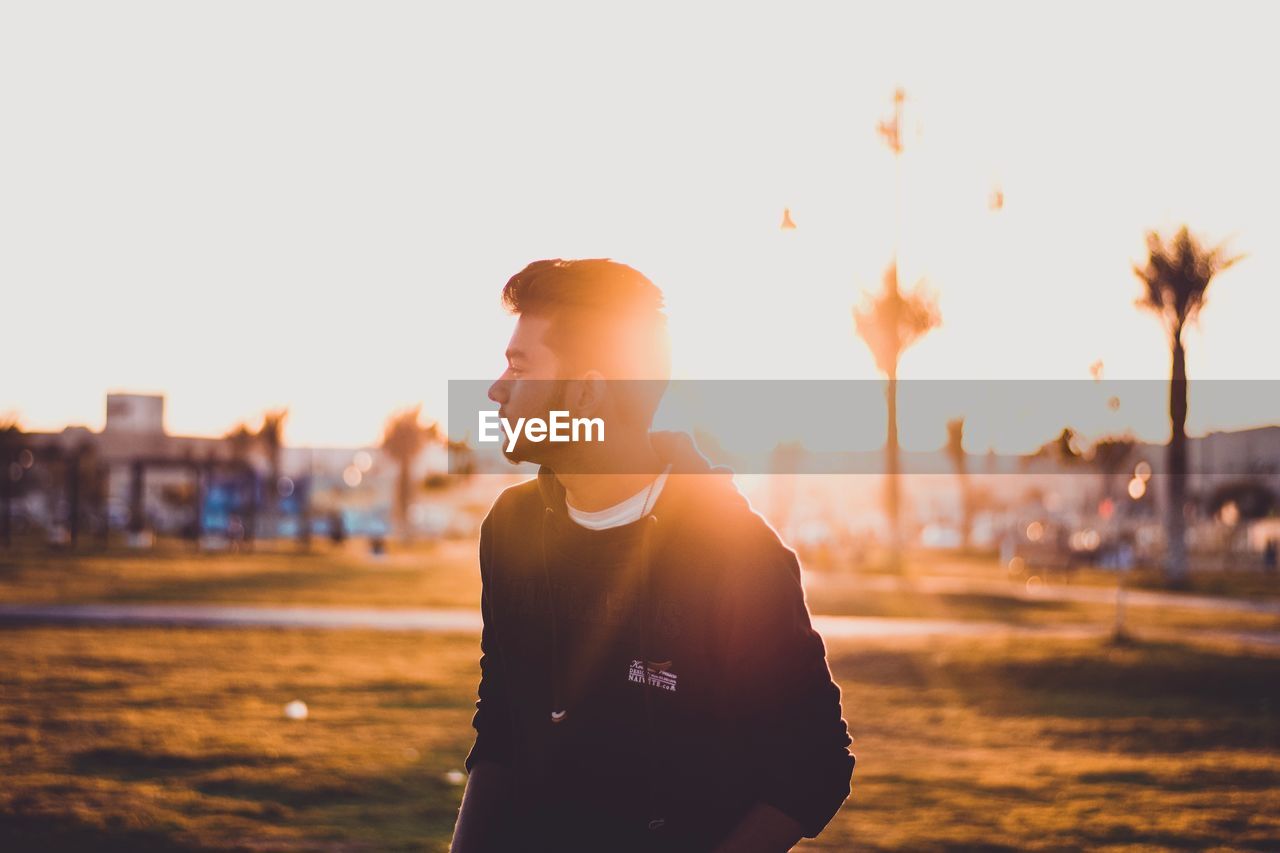 Young man standing on field during sunny day