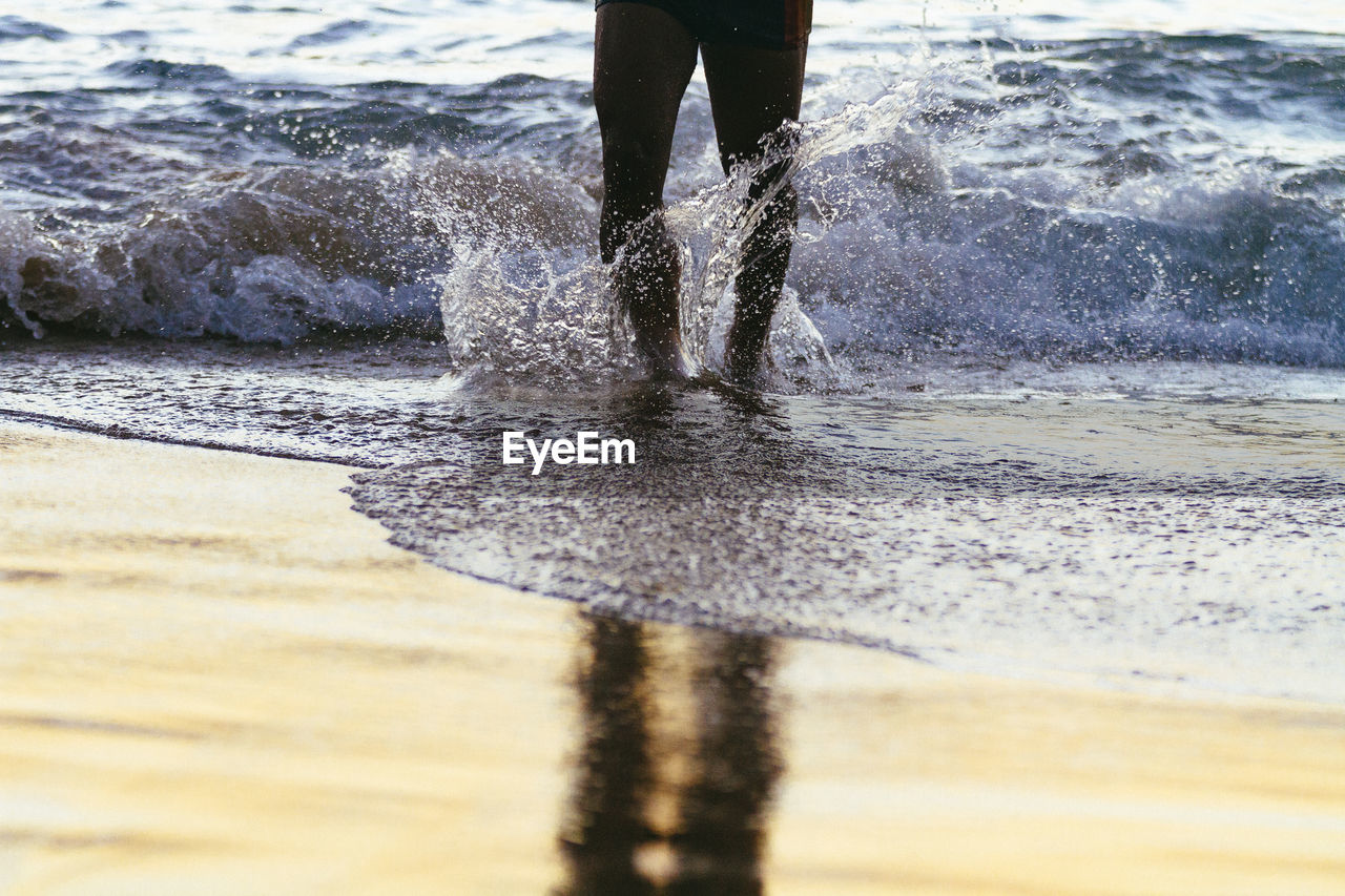 Low section of man standing on beach