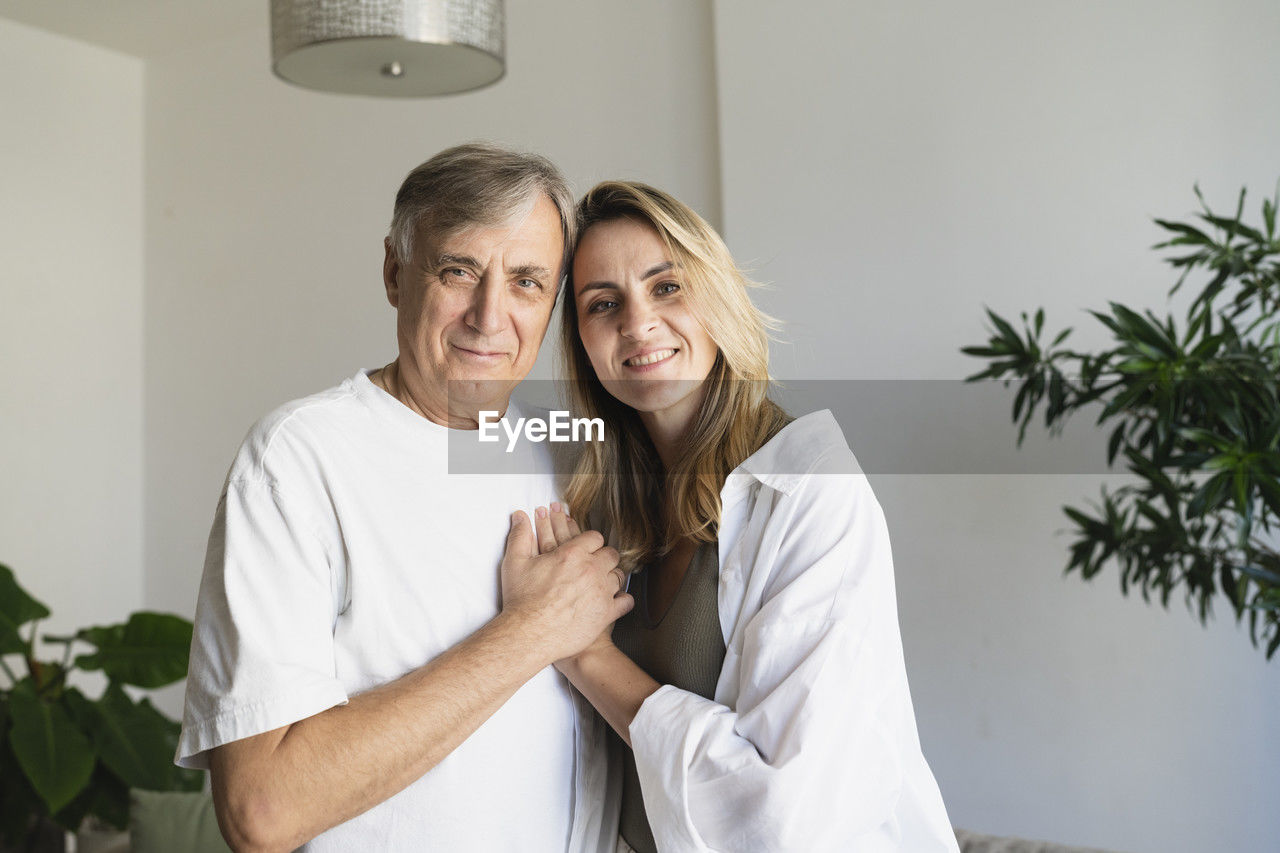Smiling blond woman standing with father at home