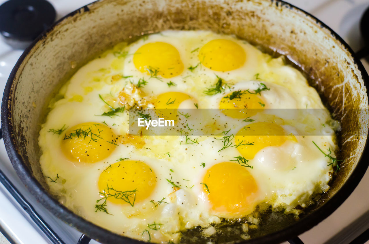 Fried eggs in the home kitchen, omelette with herbs and spices in a frying pan