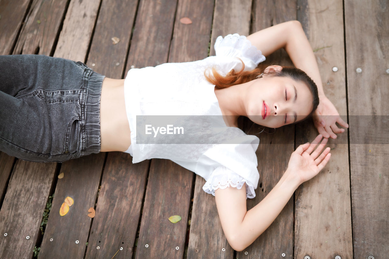 High angle view of woman lying on wooden floor