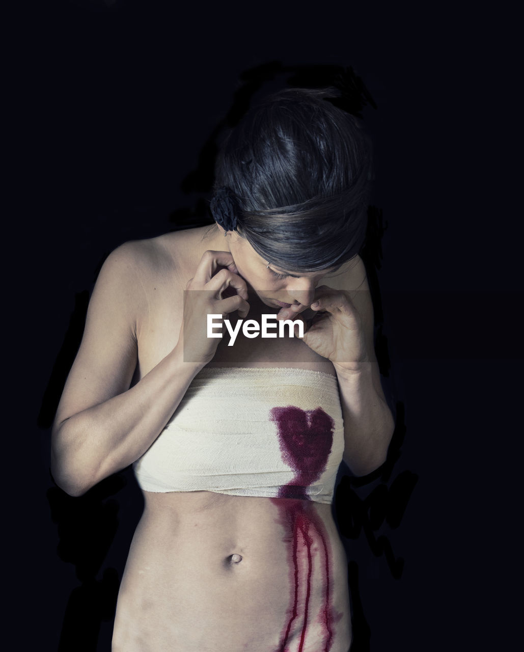 Woman with blood on bandage against black background