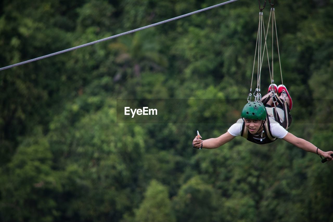 Portrait of man zip lining in forest
