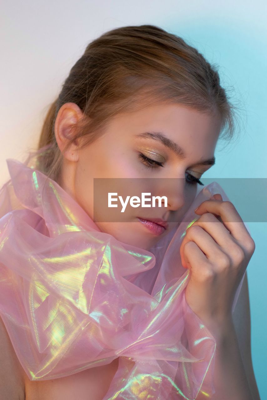 CLOSE-UP PORTRAIT OF A BEAUTIFUL YOUNG WOMAN HOLDING A HAIR