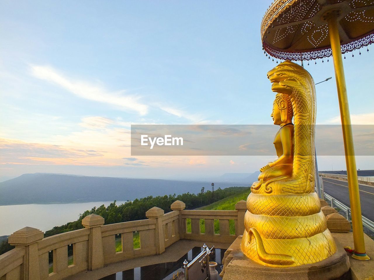 Golden statue of buddha against sky during sunset