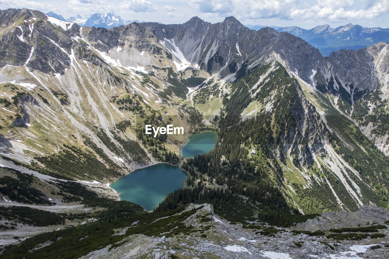 Aerial view of lake amidst mountains against cloudy sky