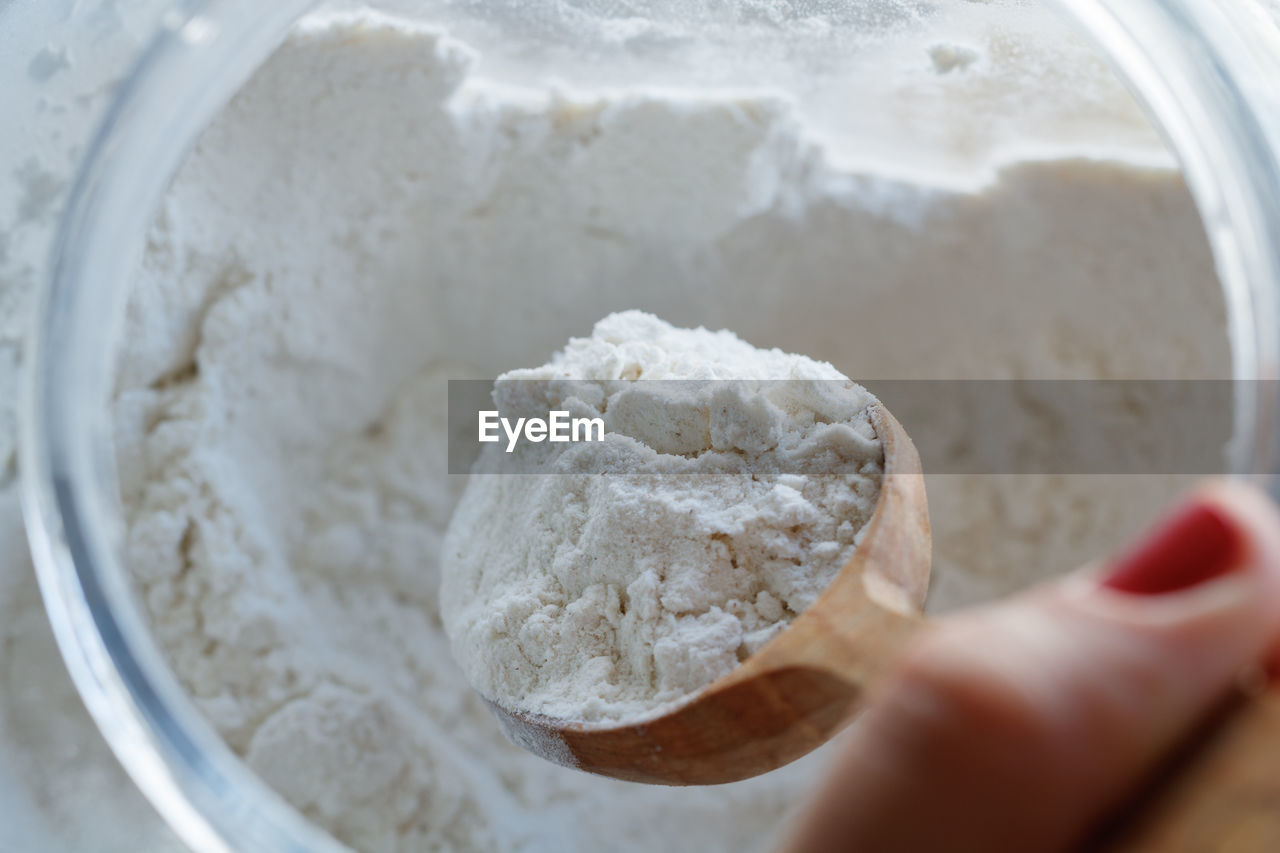 High angle view of woman hand removing flour from wooden spoon