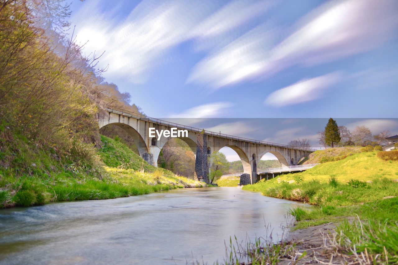 Arch bridge over river against sky