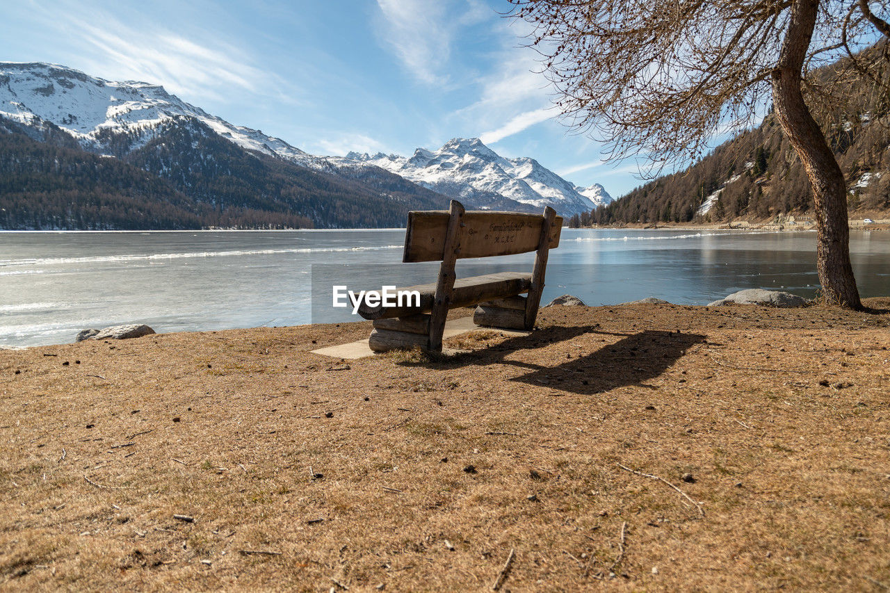 Silvaplana, switzerland, feb 21, 2023 cozy bench at the lake of silvaplana and the mount corvatsch 