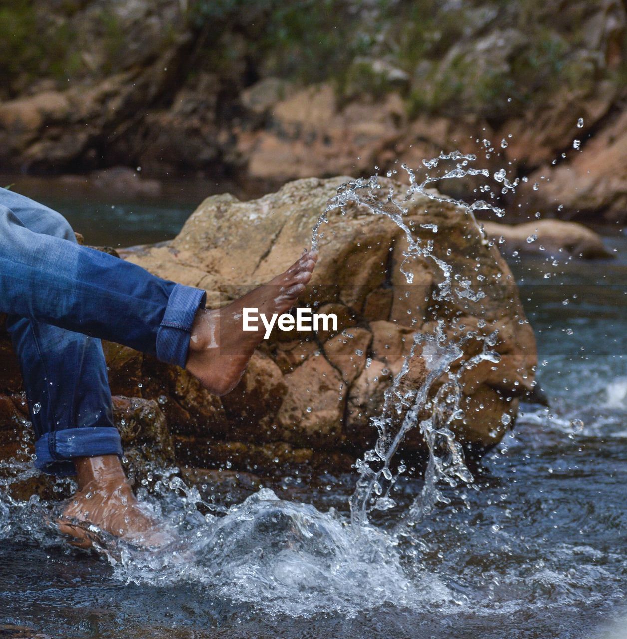 Low section of man splashing water in river