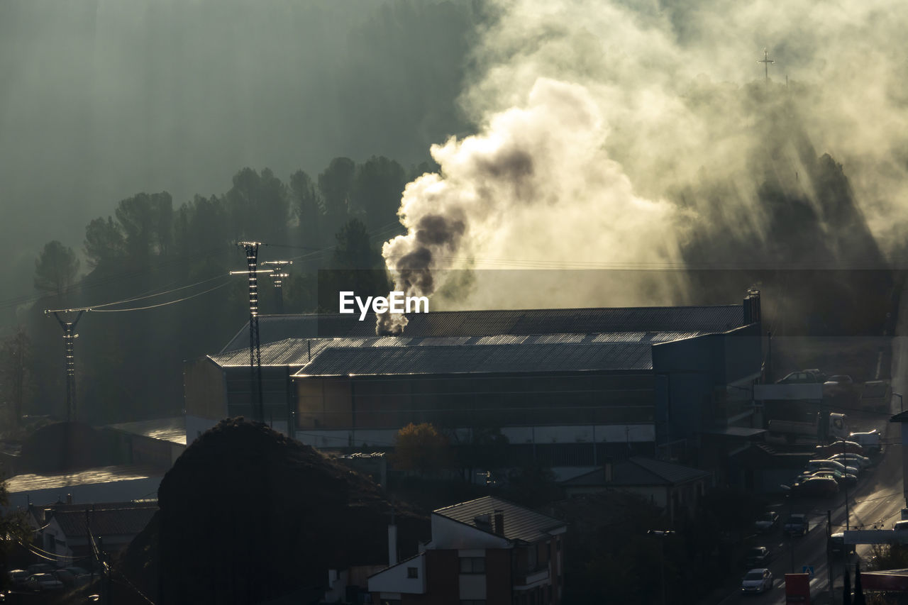 Smoke emitting from factory against sky