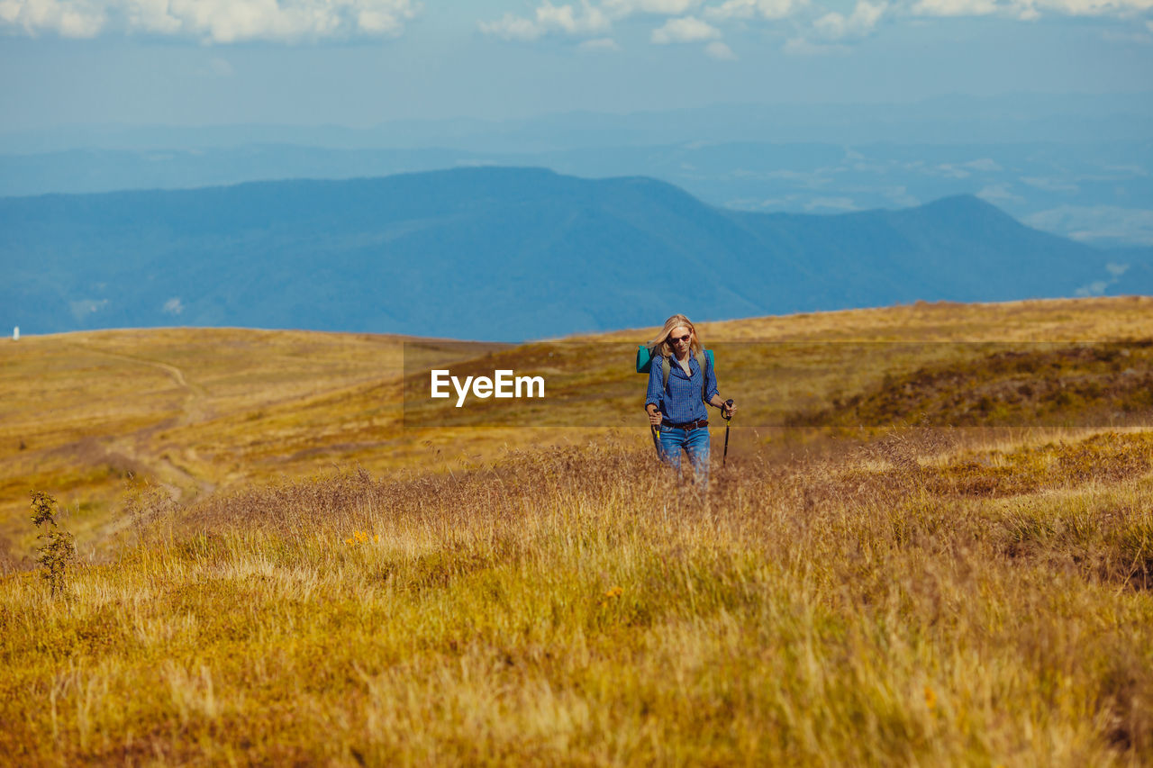 Woman walking on field against landscape