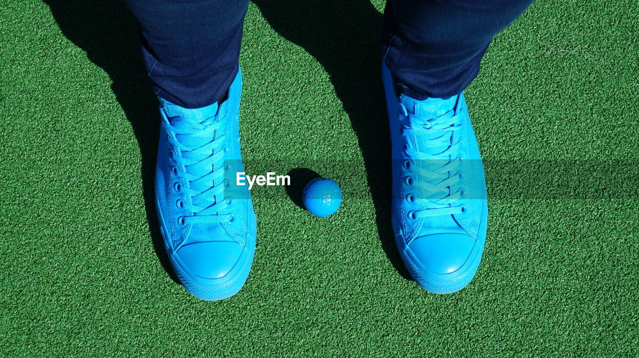 Low section of man standing with blue golf ball