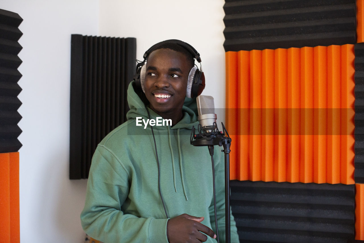 Male rapper with headphones standing in recording studio