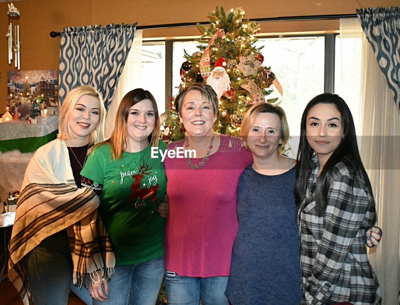 Portrait of smiling female friends standing against christmas tree