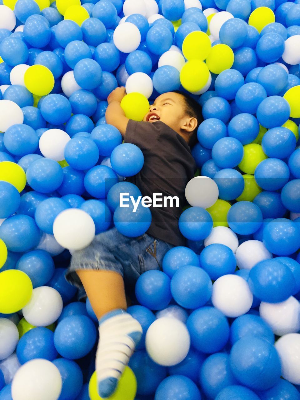 Cute boy playing with balls in pool