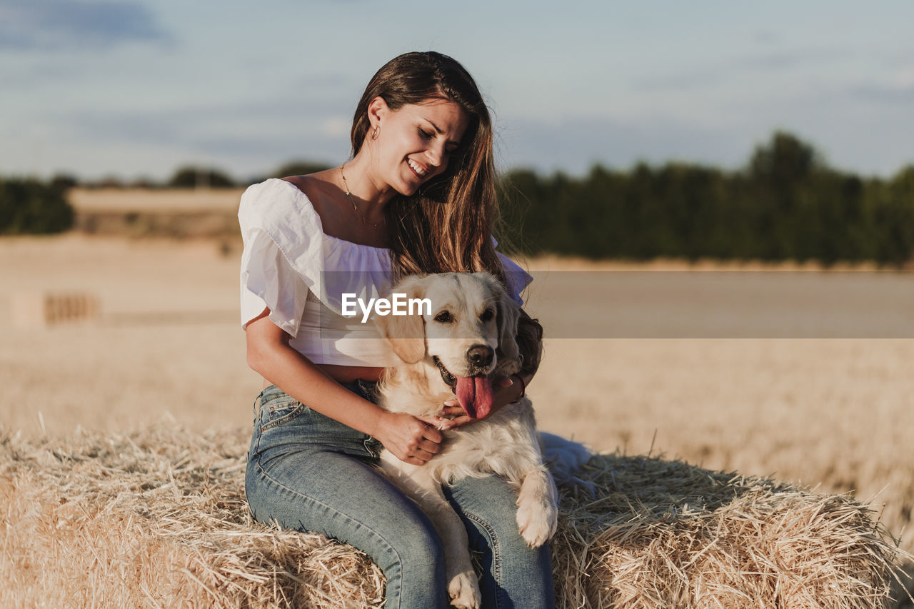 Mid adult woman with dog on agricultural field