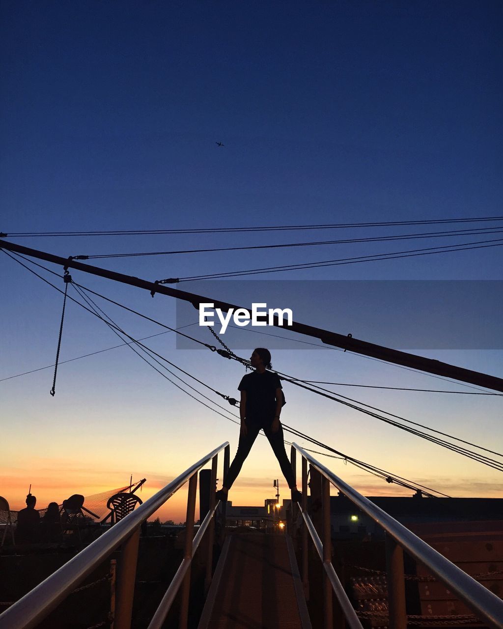 Low angle view of woman standing on overpass railing against sky