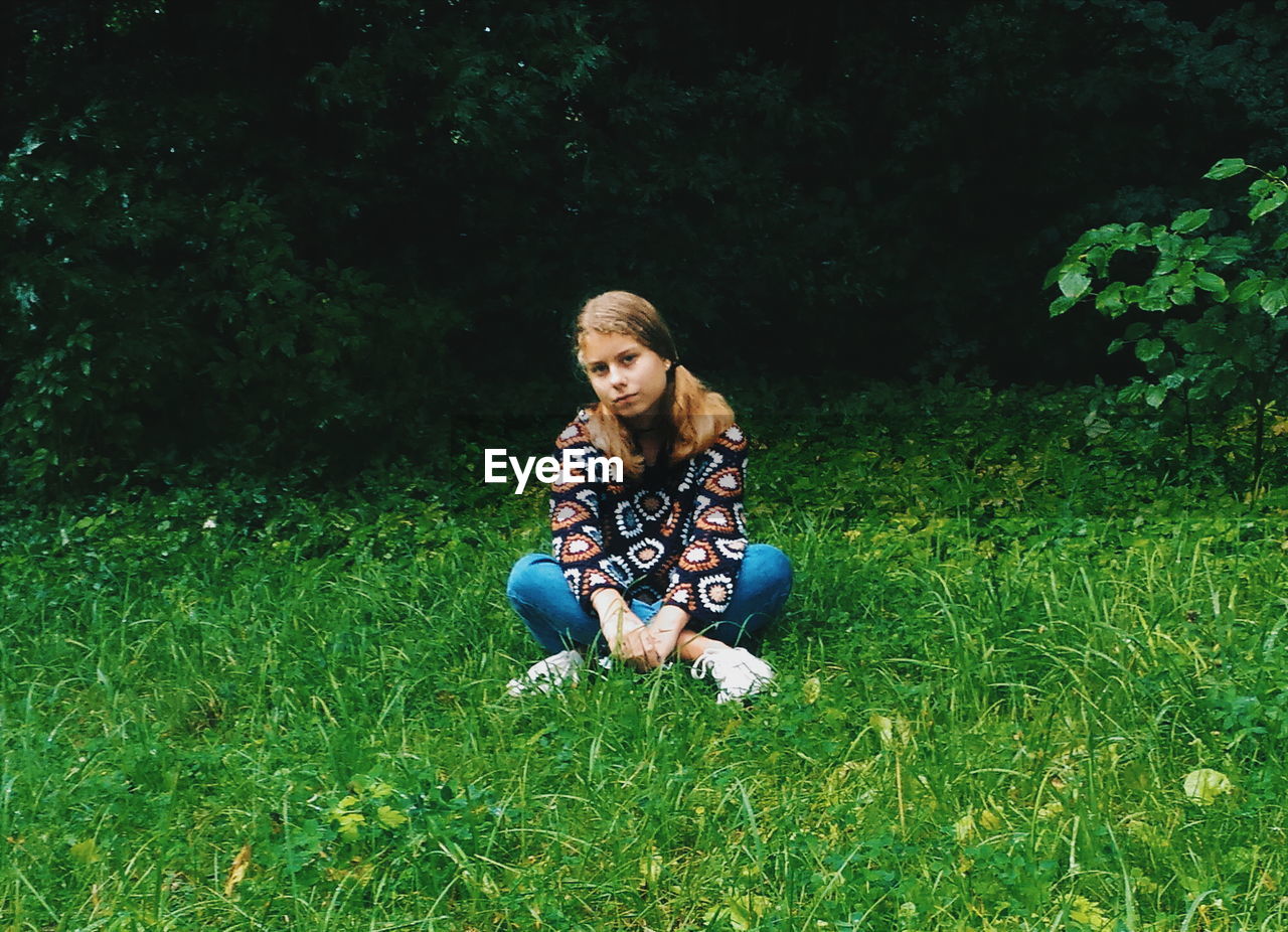 Full length of girl sitting cross legged on grassy field