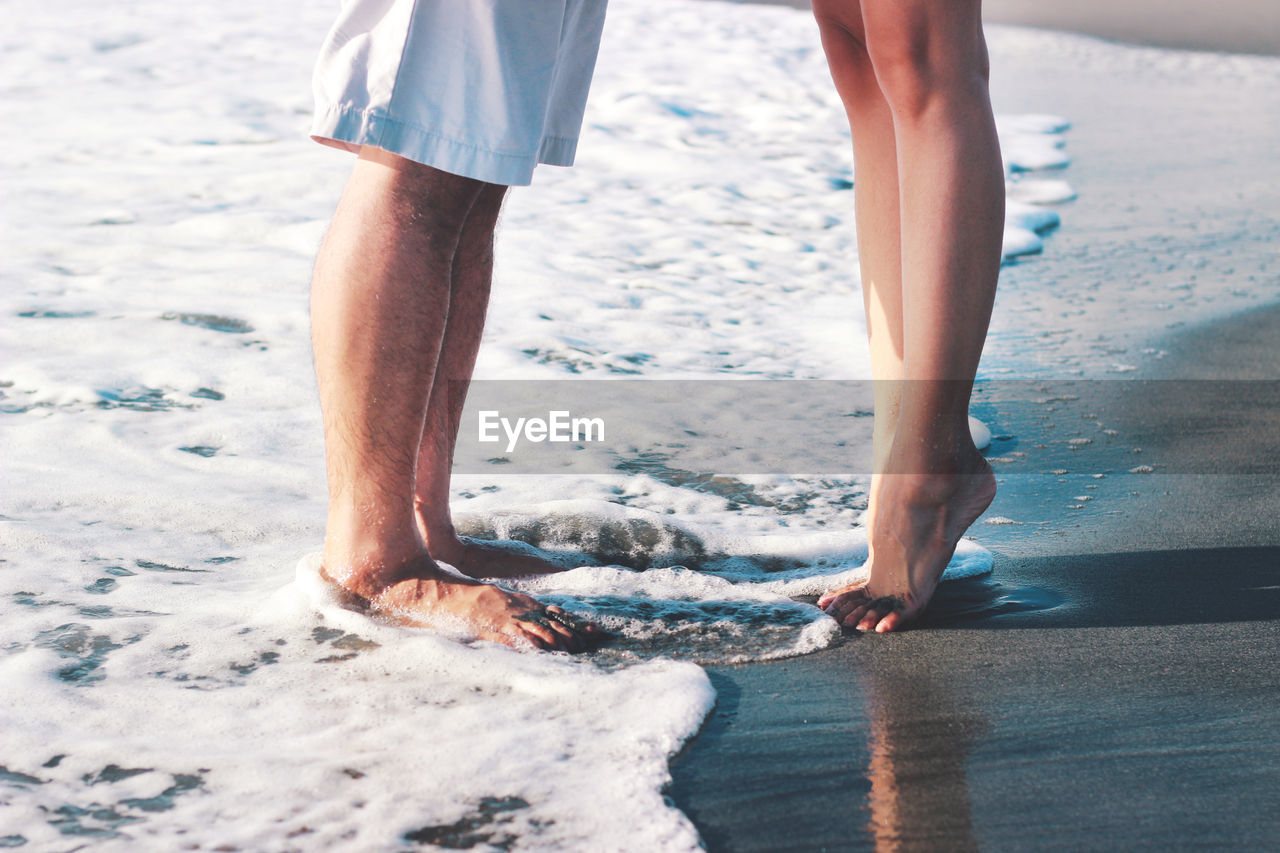 Low section of couple standing on beach