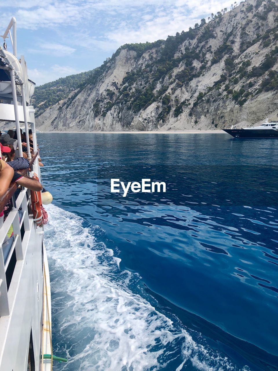 PERSON SAILING ON SEA AGAINST MOUNTAINS