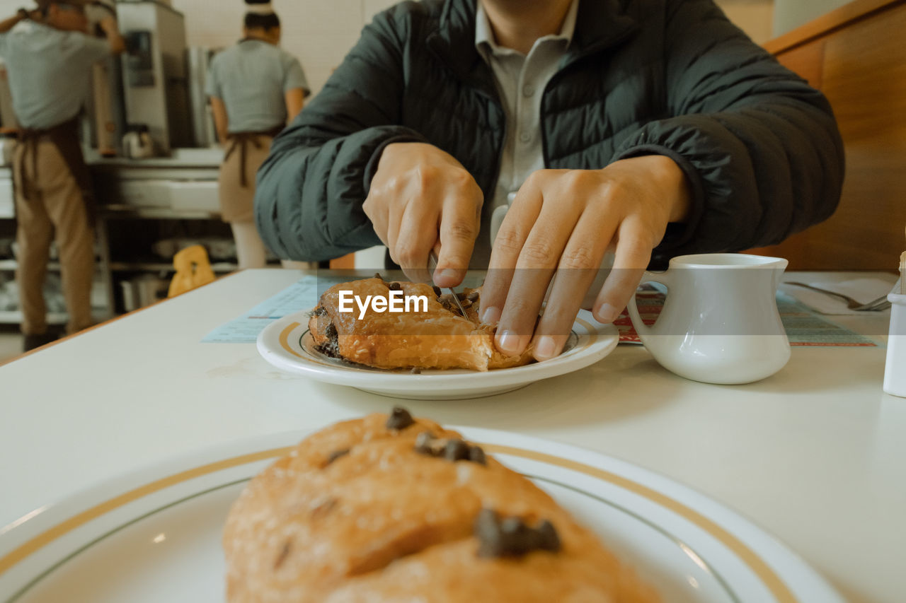 Midsection of man cutting food at table