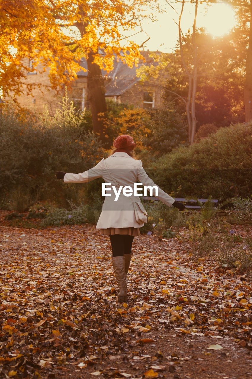 Rear view of woman walking in park during autumn