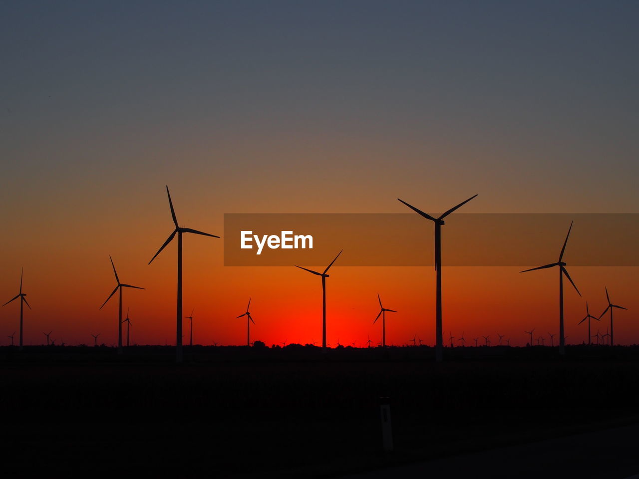 Silhouette wind turbine against sky during sunset