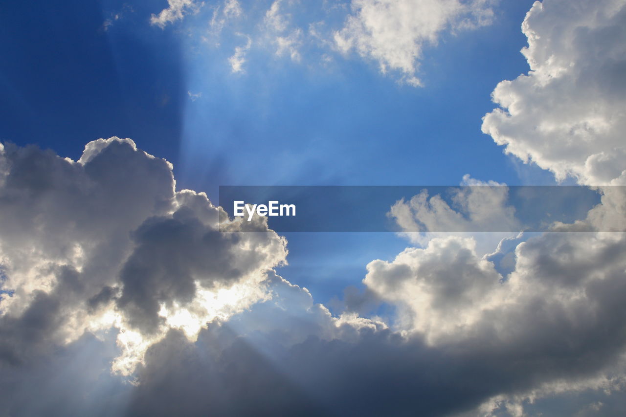 LOW ANGLE VIEW OF SUN STREAMING THROUGH CLOUDS