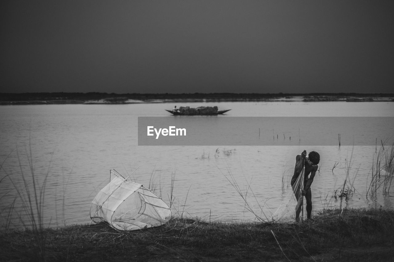 MEN IN BOAT AGAINST SKY