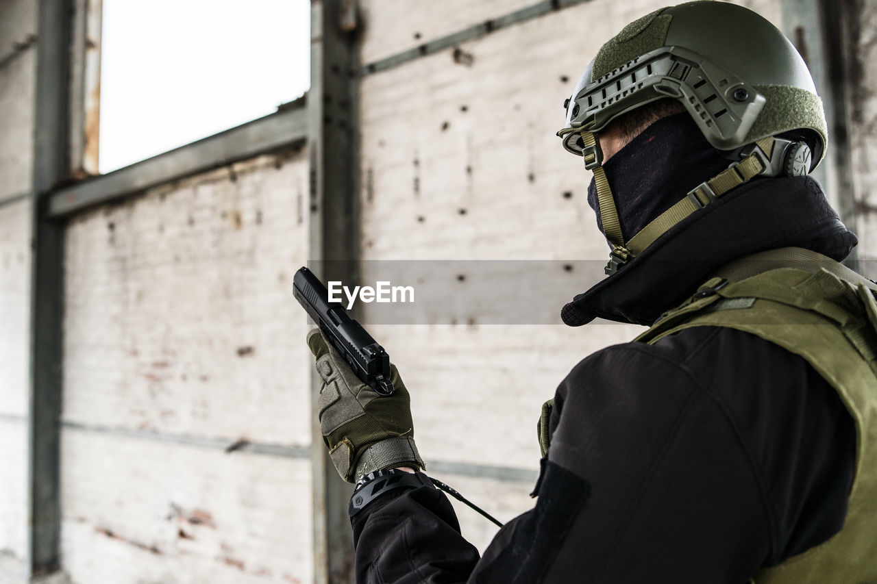 Army soldier holding gun while standing in building