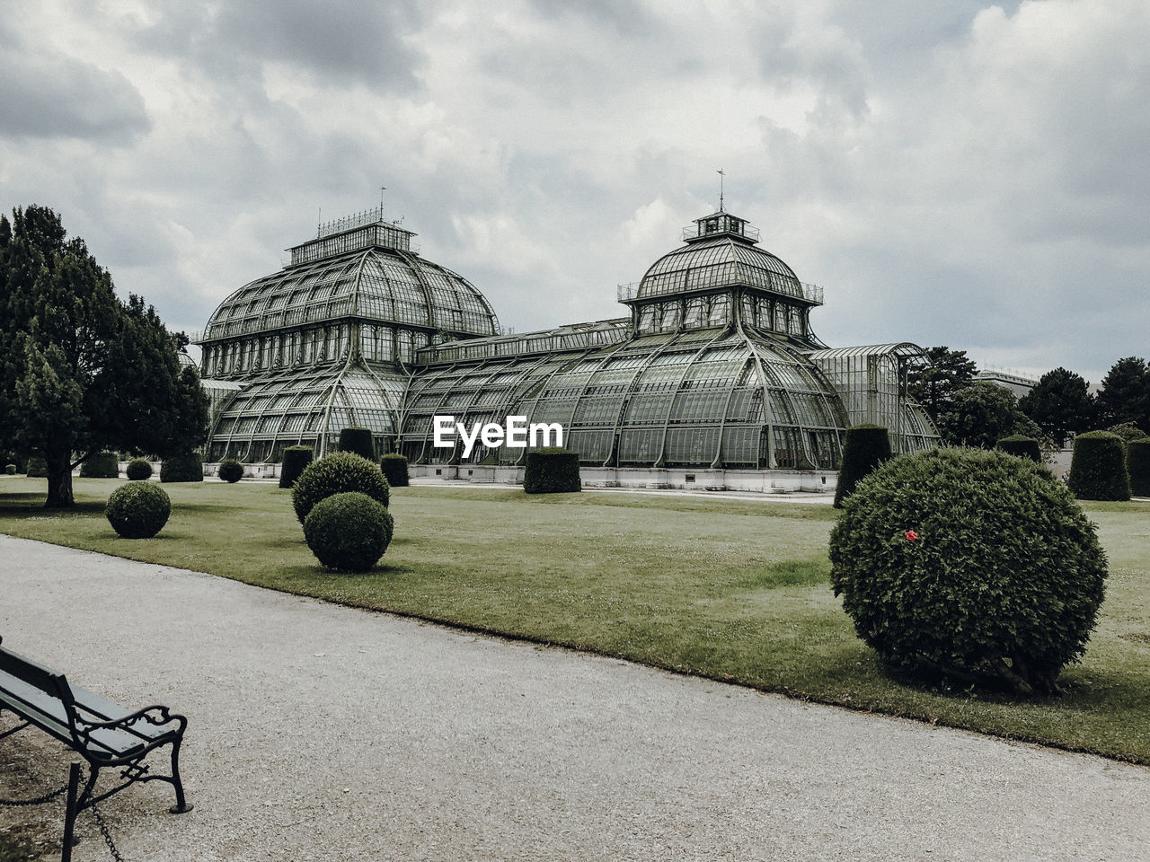 Garden by building against cloudy sky