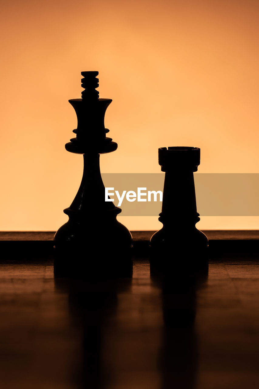 CLOSE-UP OF CHESS ON TABLE AGAINST ORANGE SKY