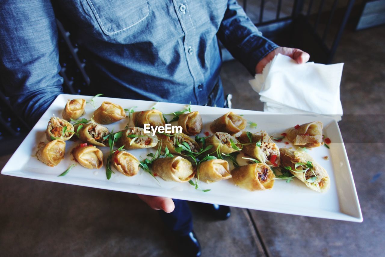 High angle view of man holding tray of fried wontons