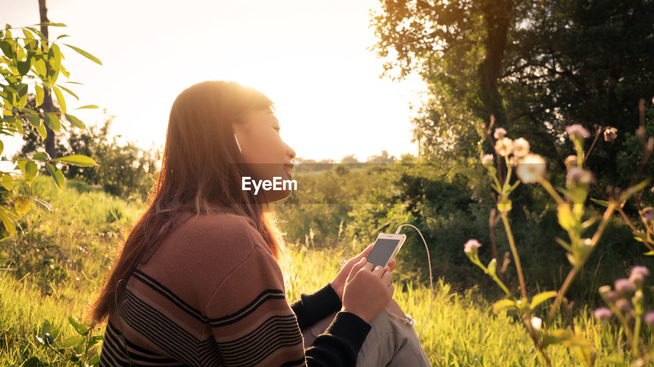 REAR VIEW OF WOMAN USING MOBILE PHONE