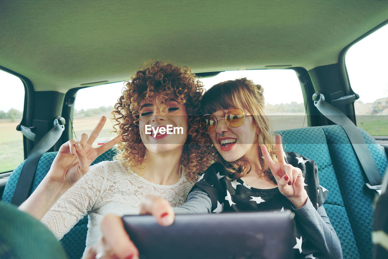 Cheerful female friends taking selfie while sitting in car