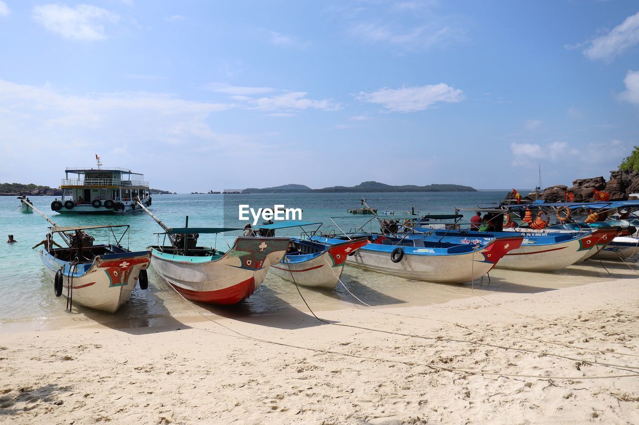 Boats moored on beach against sky