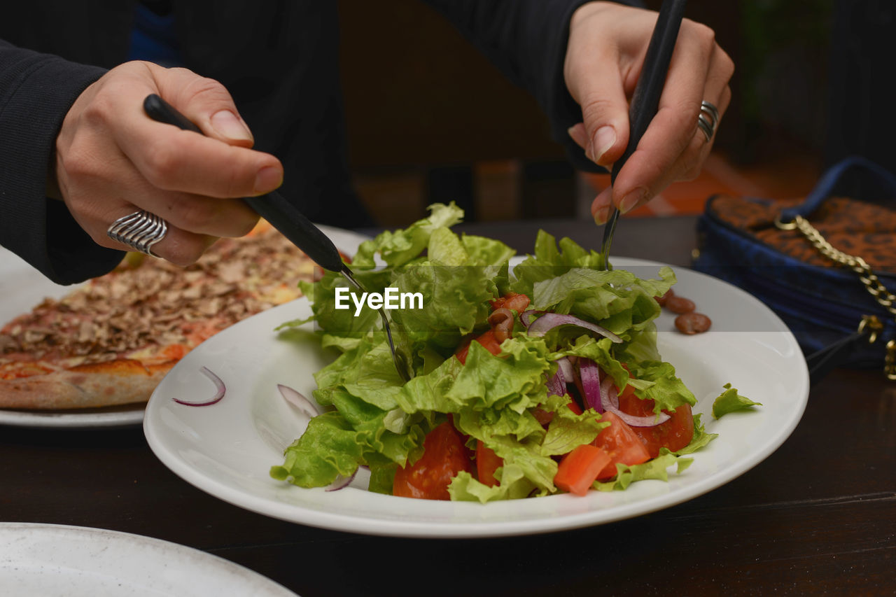 Midsection of person having salad served on table