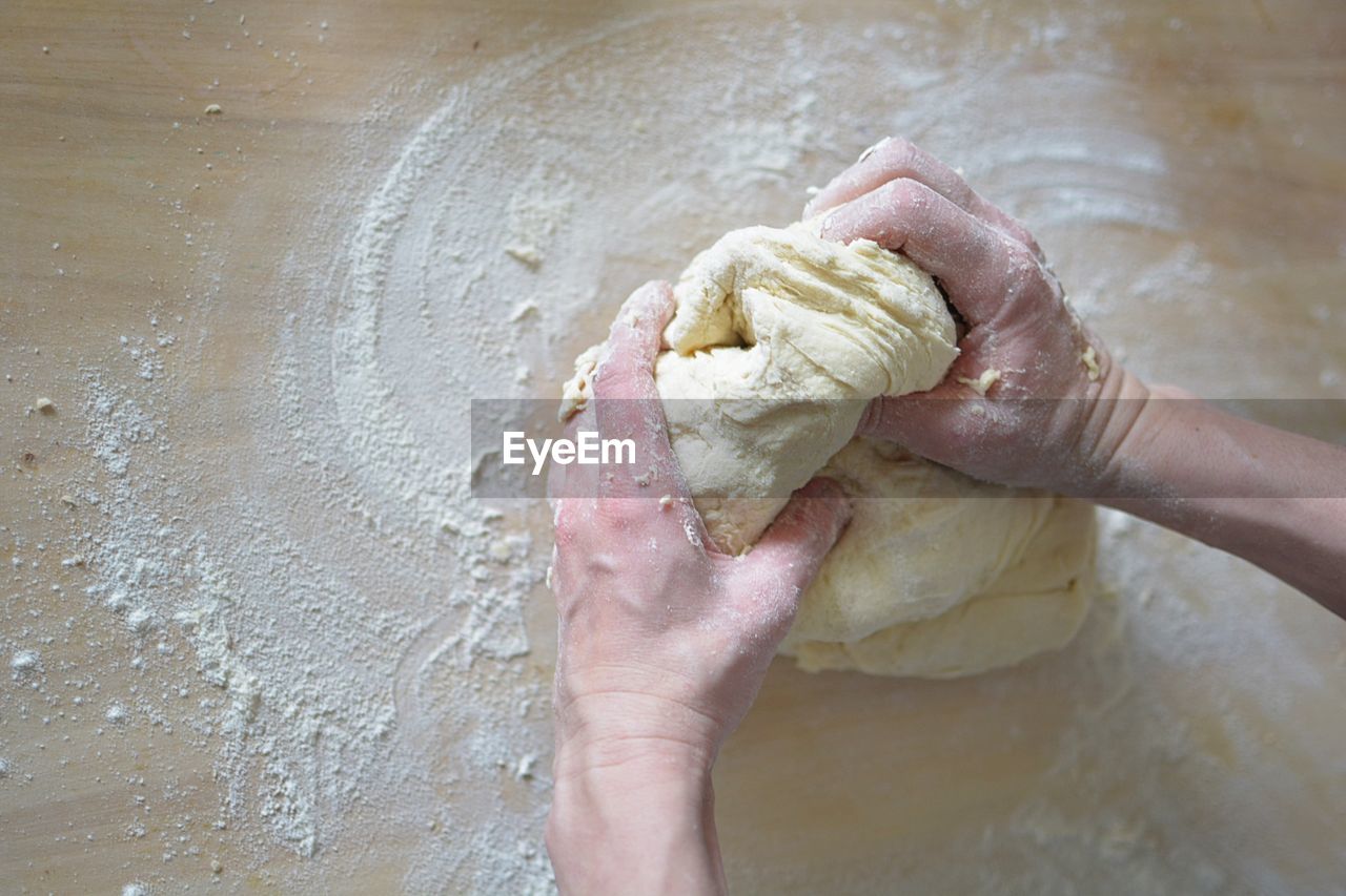 CLOSE-UP OF HAND HOLDING ICE CREAM ON TABLE