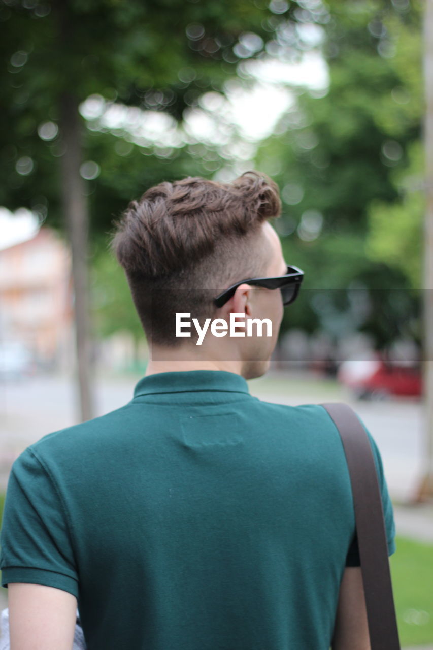 Rear view of young man looking away while standing outdoors