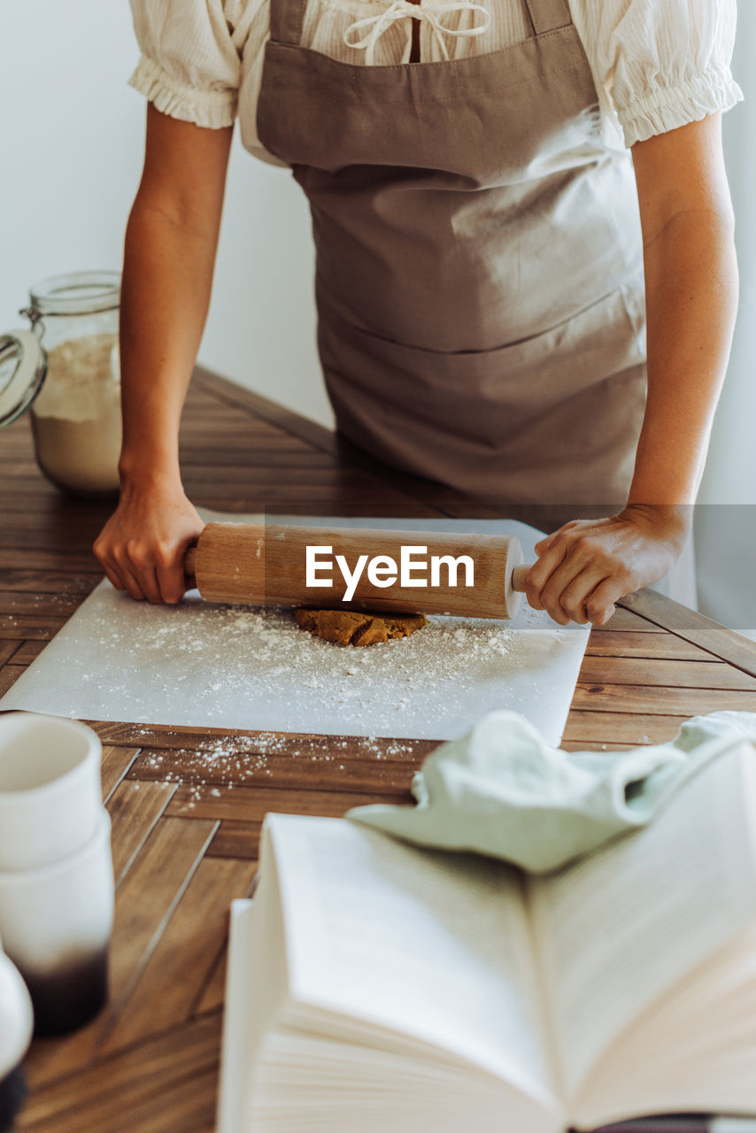 Midsection of a woman rolling dough for cookies at domestic kitchen