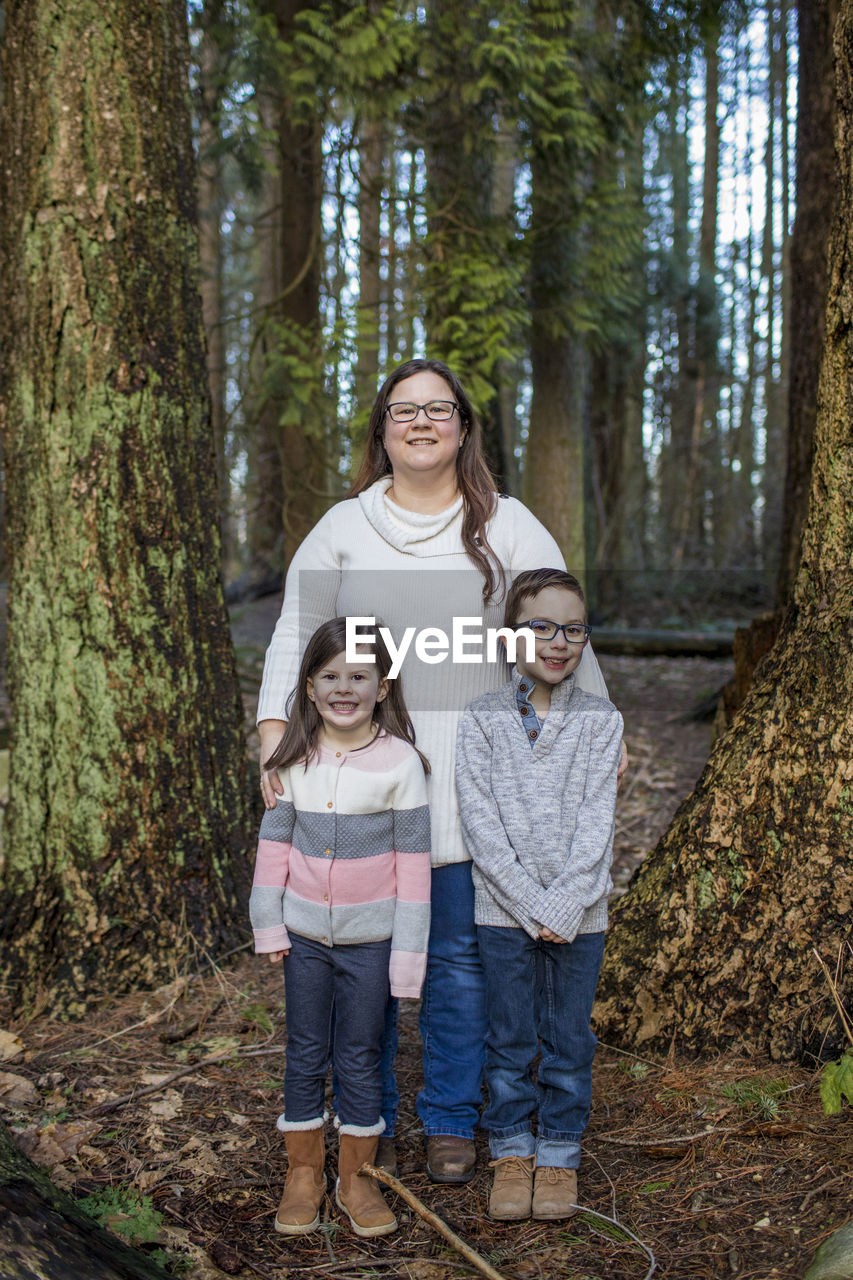 Portrait of mother with her two children in forest.